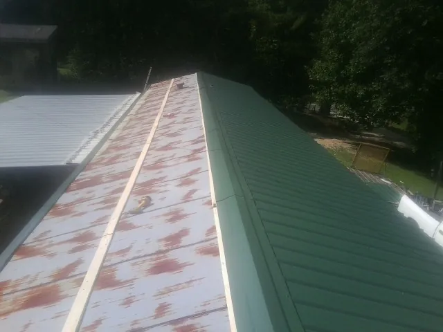 Old rusted panels beside newly installed green metal roofing in Lebanon